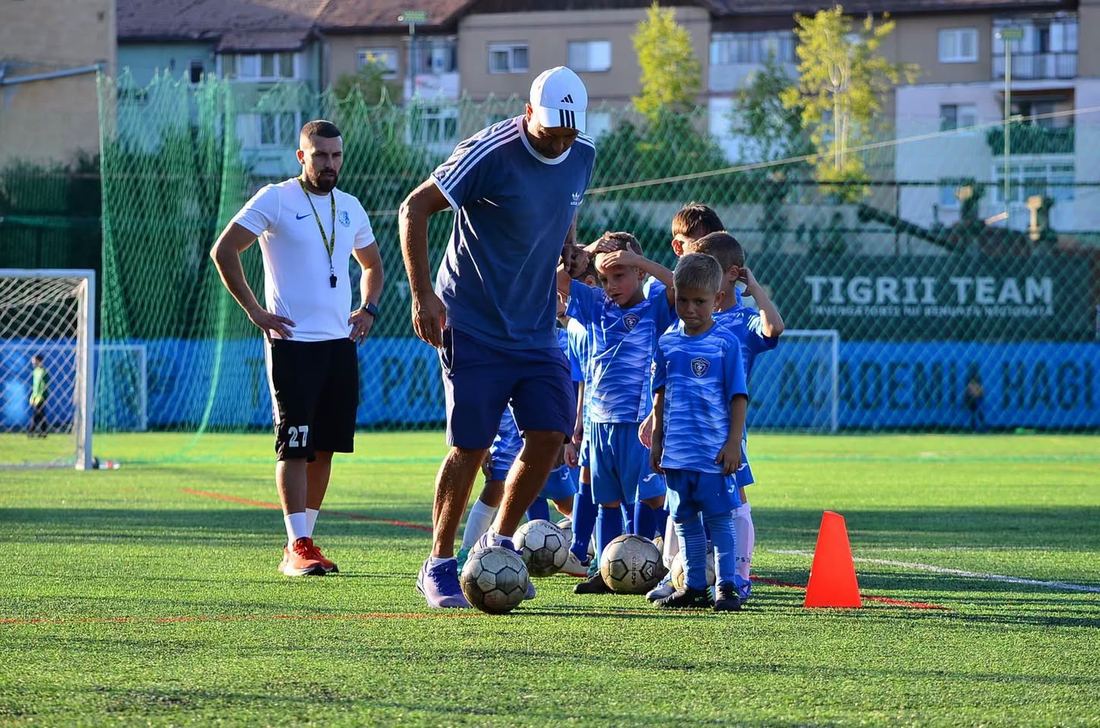Antrenor care lucrează cu mingea alături de copii mici, la Casa Tigrilor